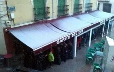 Algunos cofradres, bajo el toldo de una cafetería.