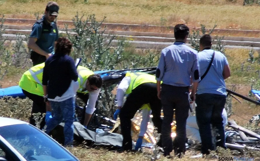 Un momento del levantamiento del cadáver al lado del aparato calcinado por el impacto.