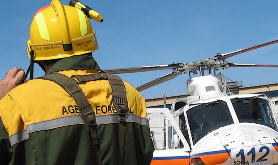 Un agente medioambiental ante un helicóptero del 112.
