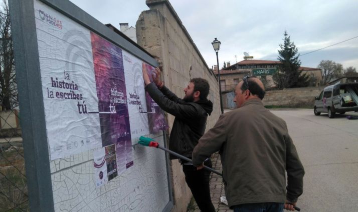Juan Carlos García, en segundo término, pegando carteles de la coalición en San Leonardo. /UP