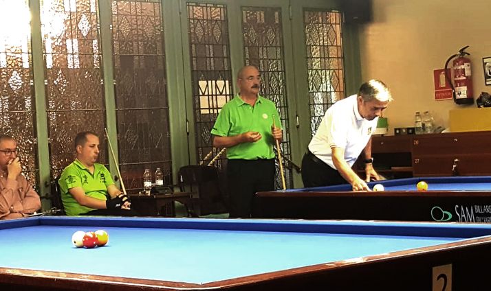 Camarero, de pie con polo verde juno a Cortés, sentado. /CAN