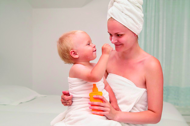 Bebé, sentado en el regazo de su mamá tras salir del baño. 