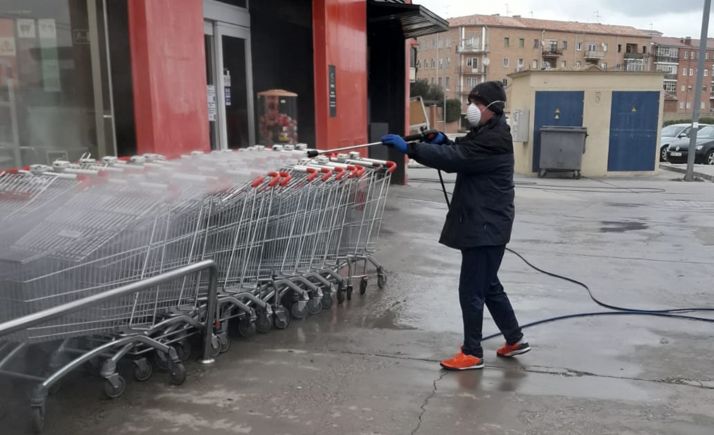 Un operario de limpieza en el exterior de un supermercado en Almazán. 