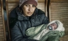 Lyuba, con su hijo de dos meses en brazos, espera sentada en una estación de tren en la ciudad Uzhhorod, (Ucrania). / Olena Hrom
